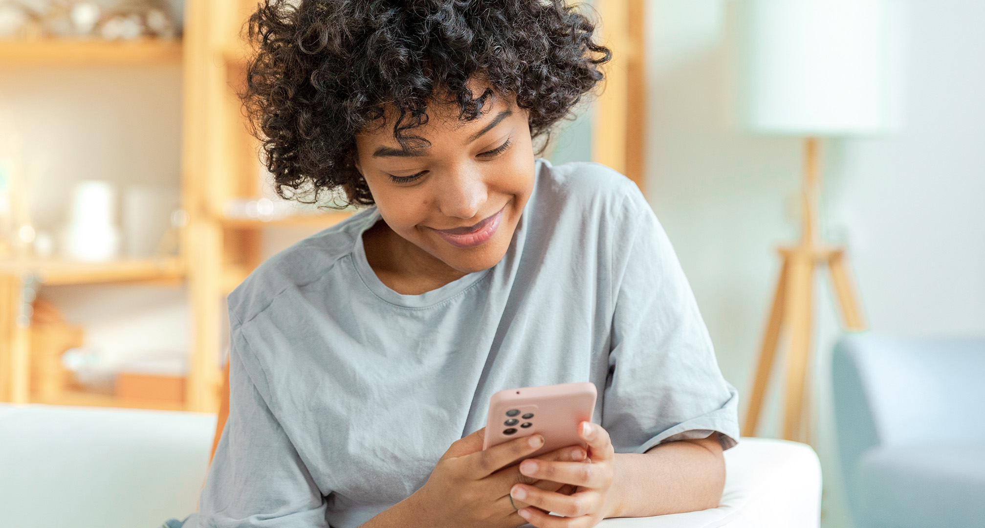 Nahaufnahme einer lächelnden Person, die auf ihr Mobiltelefon schaut