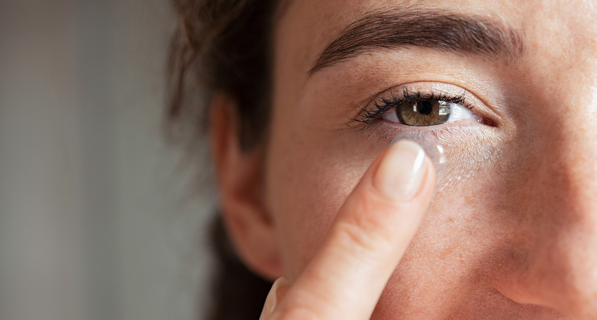 Nahaufnahme einer Person, die eine Kontaktlinse vor dem Auge hält