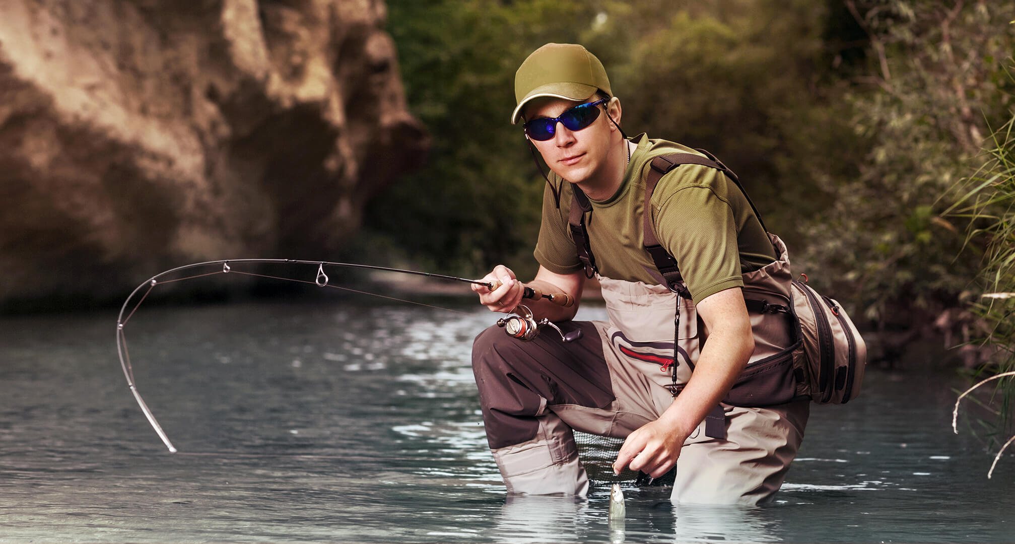 Fischer kniend im Wasser mit Sonnenbrille